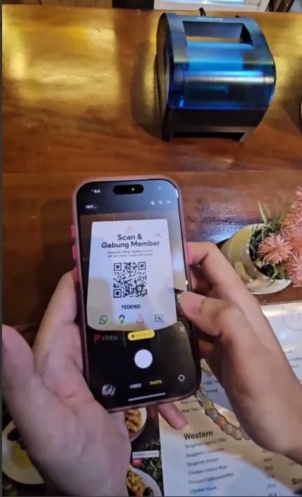 Pelanggan mengarahkan kamera ponsel ke kartu QR Rintis Member di meja kasir kafe